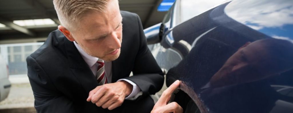 Man checking for scratches on his car